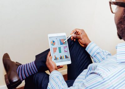 Man in striped suit looking down at ipad with financial data graphs displayed