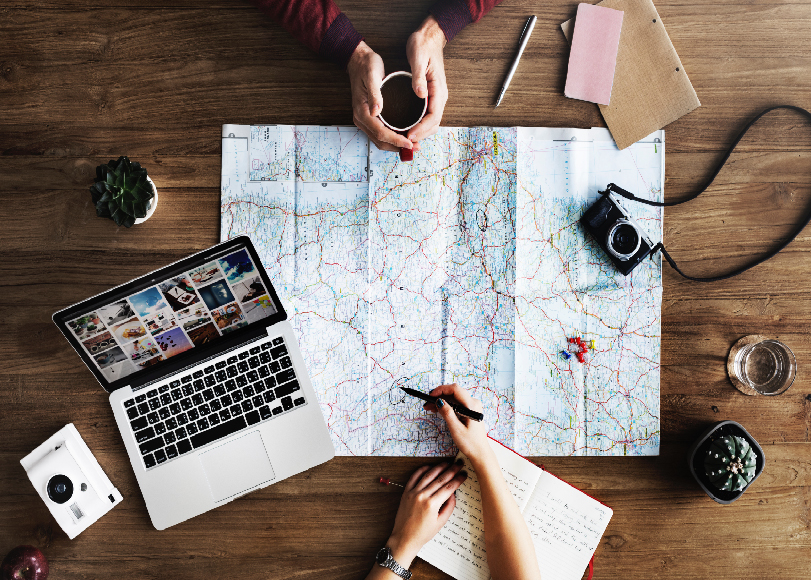 Two people meeting and planning a trip using a pen, journal, and a map