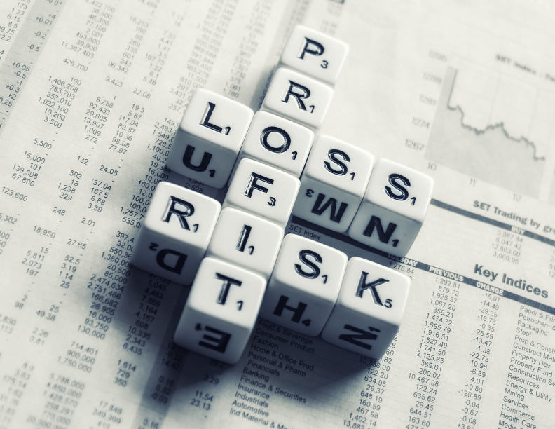 Lettered dice set in a crossword fashion and spelling the words: profit, loss, and risk